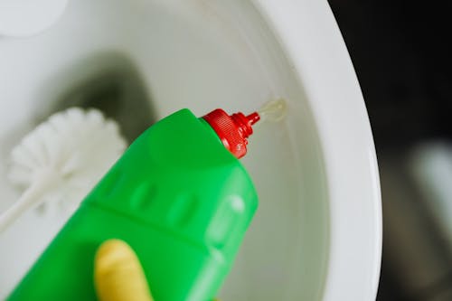 Crop person pouring liquid toilet cleaner in toilet bowl