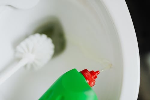 Liquid toilet cleaner pouring in toilet bowl