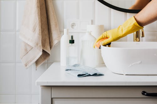 Free Person in glove wiping surface of sink in modern bathroom Stock Photo