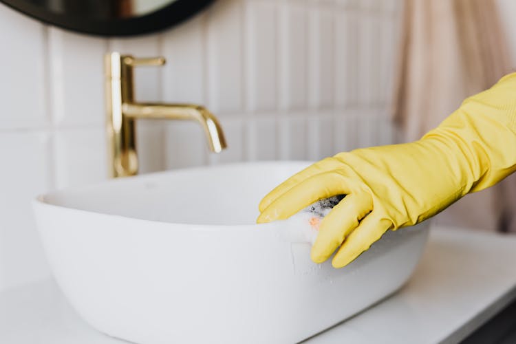 Person In Glove Cleaning Bathroom Sink