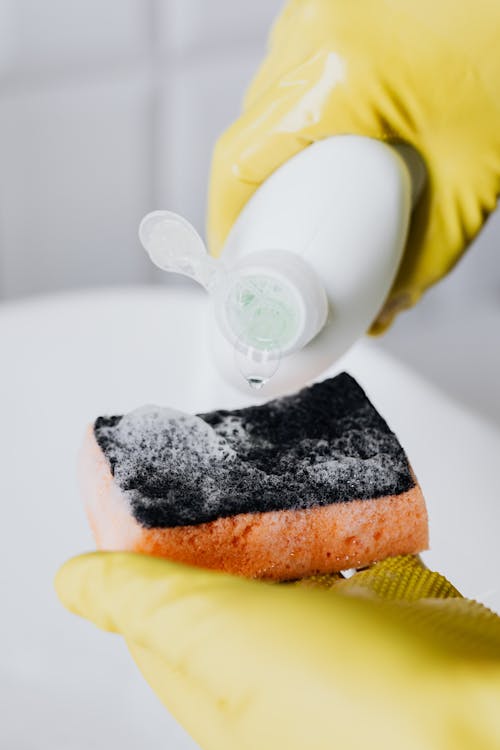 Free Crop person pouring detergent on sponge Stock Photo