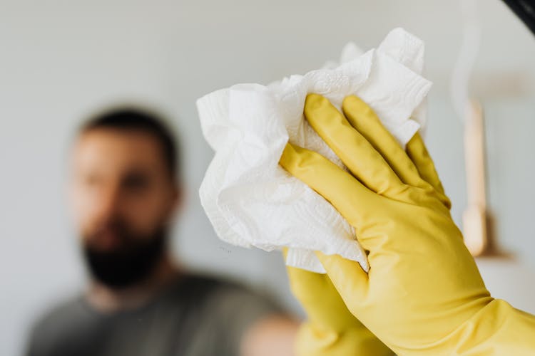 Crop Man Cleaning Mirror In Bathroom