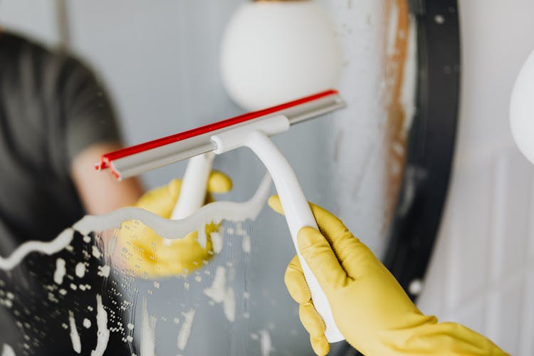 Anonymous Person Drying Mirror With Squeegee