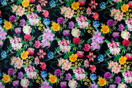 Vibrant floral fabric design with assorted flowers on dark background.