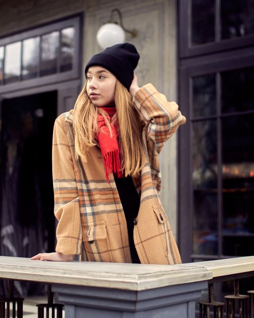 Free Caucasian woman in winter clothing posing outdoors on a city balcony, showcasing modern fashion style. Stock Photo