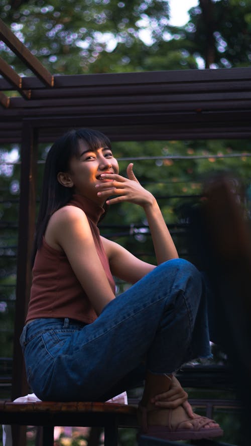 Cheerful young Asian lady having fun on terrace of cafeteria