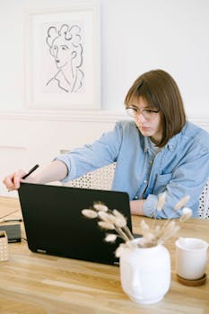 A woman in a home office working on a laptop, illustrating remote work lifestyle.