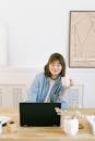 Woman Drinking Coffee and Looking at a Laptop