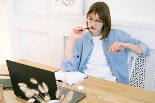 Woman in Blue Denim Jacket Holding Pen and Notebook