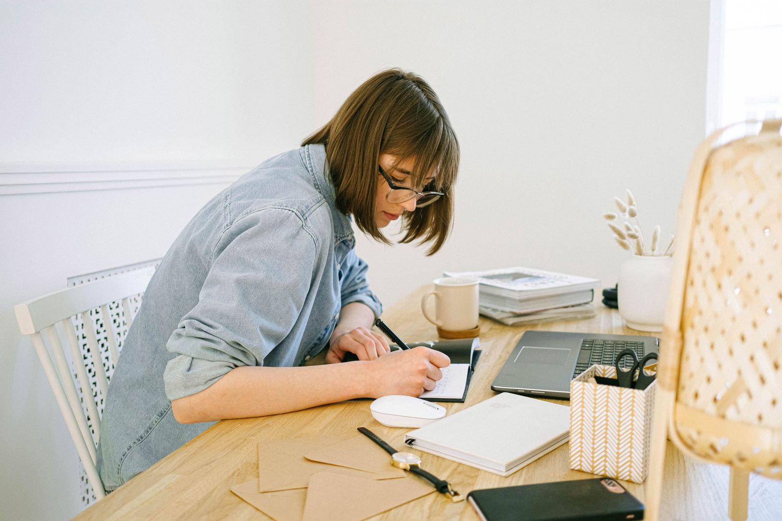 Job seeker writing notes in a notebook beside a laptop while comparing job listings