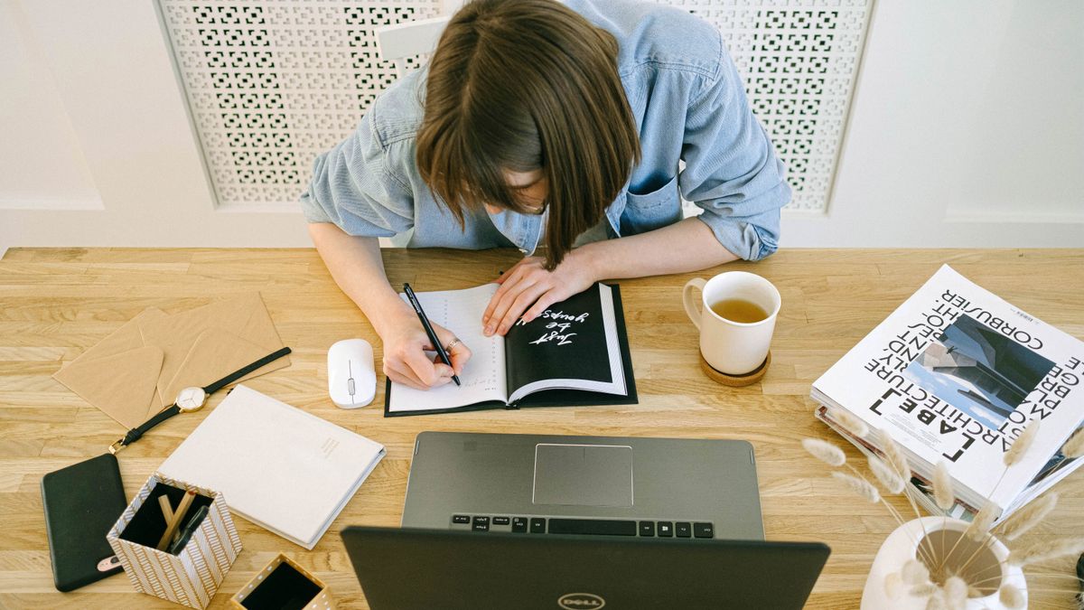 Mujer anotando información junto a un portátil para repasar frases para aclarar en inglés