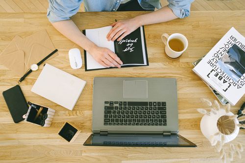 Free Top-down view of a home office desk with a laptop, coffee, and notes, perfect for freelance work or studying. Stock Photo