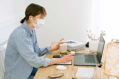 Free Woman With Face Mask Looking at a Laptop Stock Photo