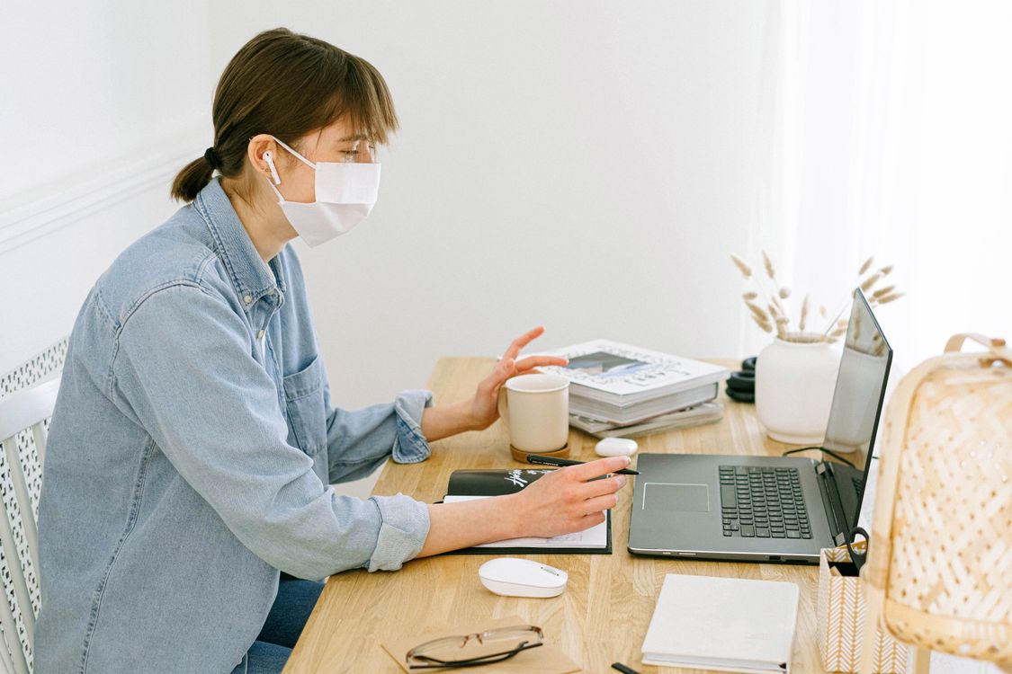 Woman With Face Mask Looking at a Laptop · Free Stock Photo