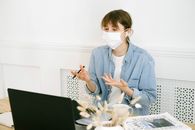 一名女子戴着口罩在家庭办公室进行视频通话