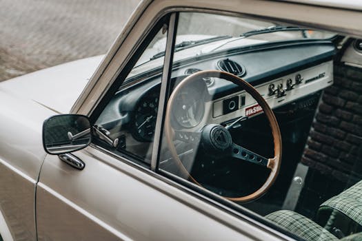 Close-up shot of a vintage car interior featuring a wooden steering wheel and retro dashboard design.