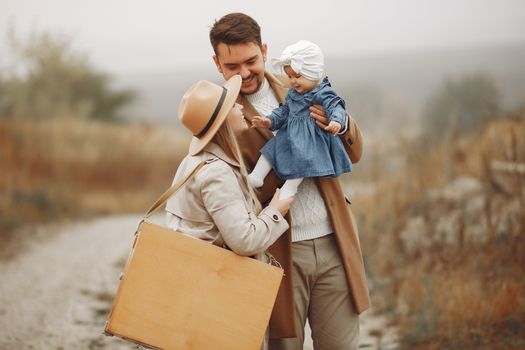 Happy family with cute baby girl smiling and having fun while spending autumn day together on nature