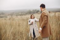 Happy young couple holding hands and enjoying autumn day in meadow