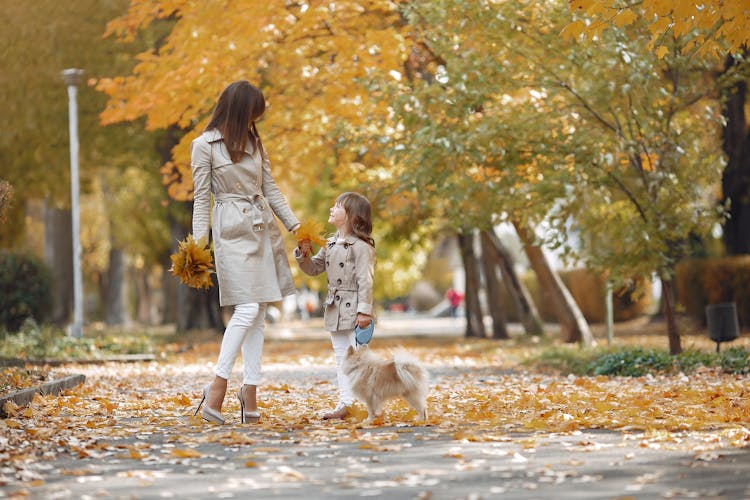 Content Mother And Daughter Walking With Dog In Autumn Park