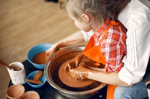 Crop mother and daughter making pot in pottery