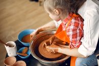 Crop mother and daughter making pot in pottery