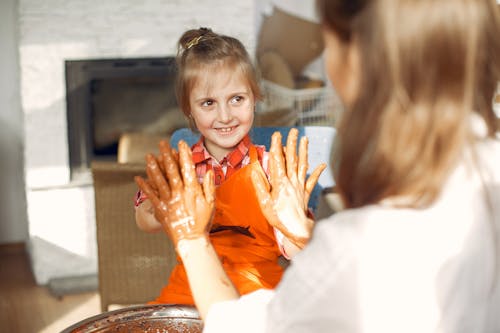 Happy mother and daughters playing hand clapping game in pottery