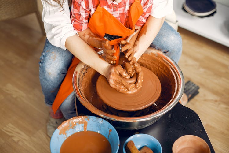 Crop Ceramist With Little Girl Working On Pottery Wheel