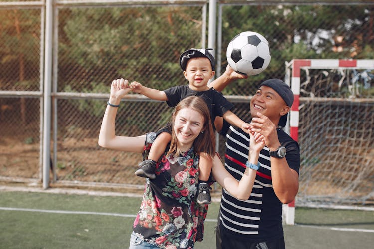 Happy Family With Ball On Football Field