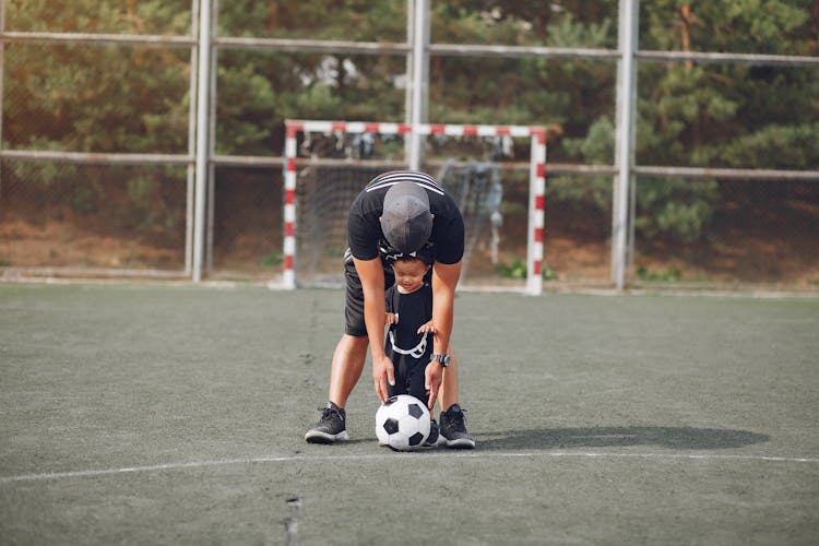 Father And Son With Football Ball On Sports Ground