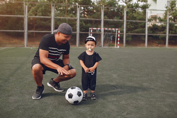 Content Father Teaching Son To Play Football