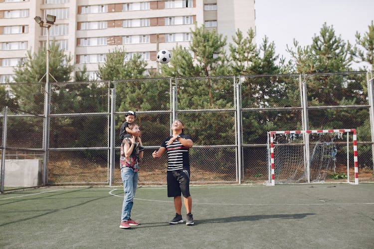 Happy Family On Spots Ground With Football Ball