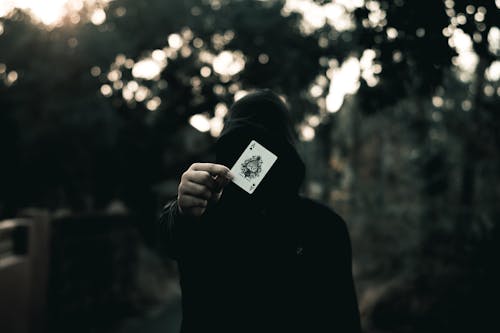 Free Person in Black Hoodie Holding a Playing Card Stock Photo
