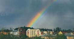 在戏剧性的天空下，一道充满活力的彩虹横跨城市景观，捕捉到城市与自然的融合