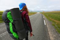 Woman in Red Jacket and Blue Knit Cap Walking on Road