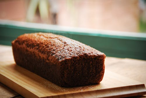 Closeup of sweet delicious fresh baked banana bread cake placed on wooden cutting board in kitchen