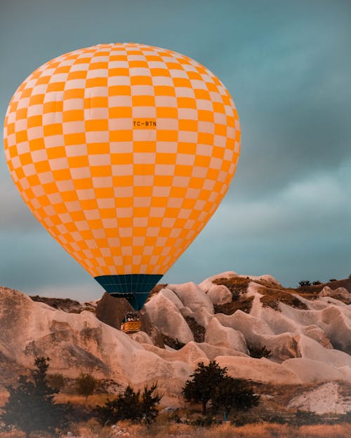 Air balloon flying over rocky formations in countryside