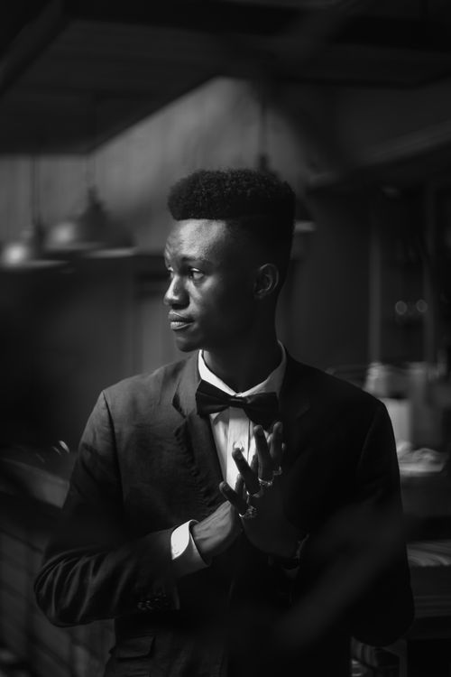 Free Elegant portrait of an African man in a suit and bow tie, looking away with a thoughtful expression. Stock Photo
