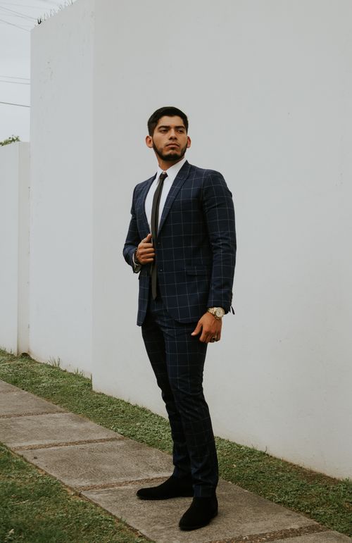 Free Full body serious bearded male executive with dark hair in formal wear standing near white wall Stock Photo