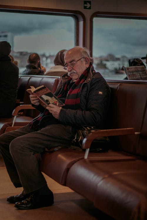 Senior man reading book in bus terminal