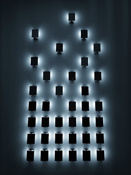 Rows of small black rectangular glowing luminaries on wall in dark room at night