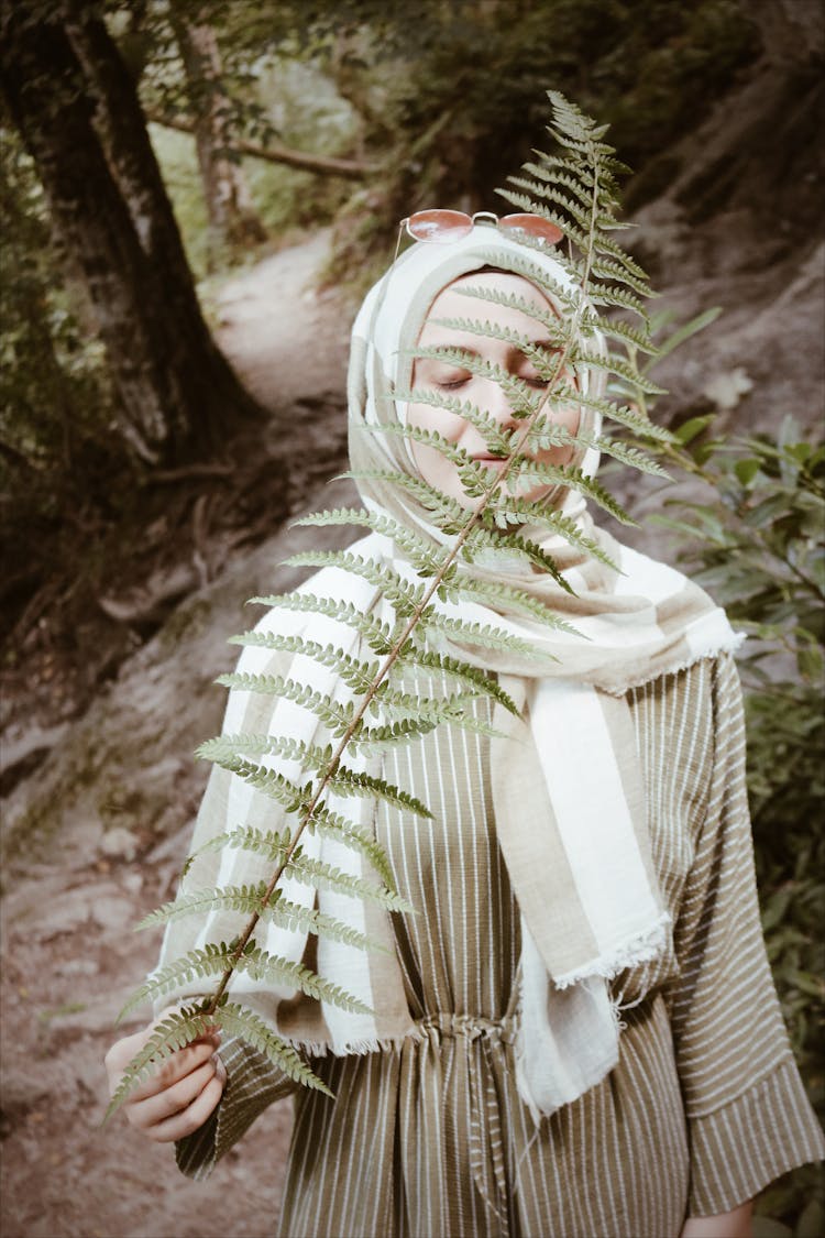 Woman Sniffing Leaf Blade Of Fern