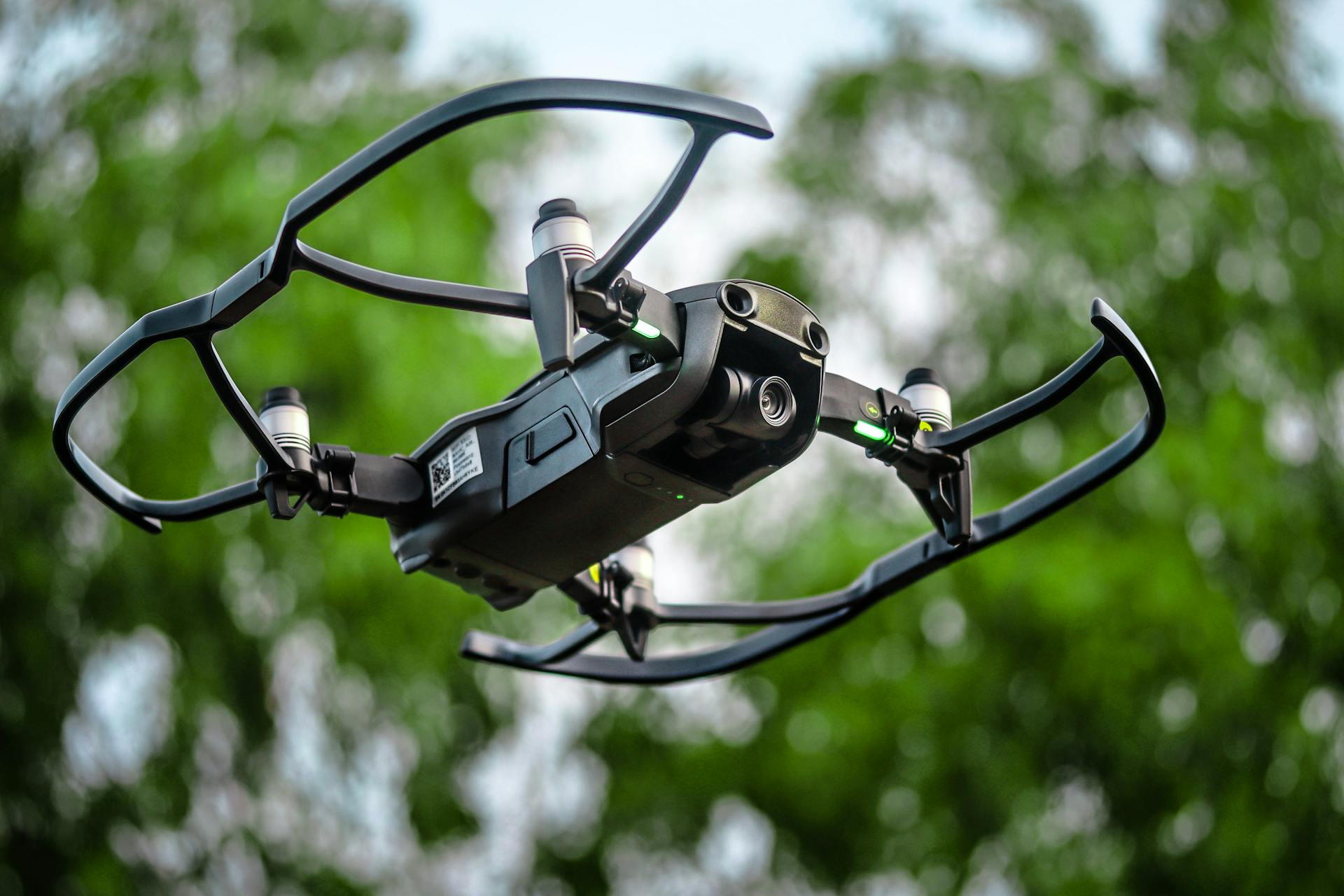 Close-up of a drone in flight with green foliage background, showcasing high-tech features.