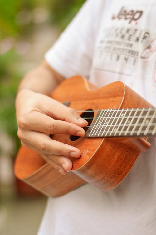 Crop person practicing to play ukulele