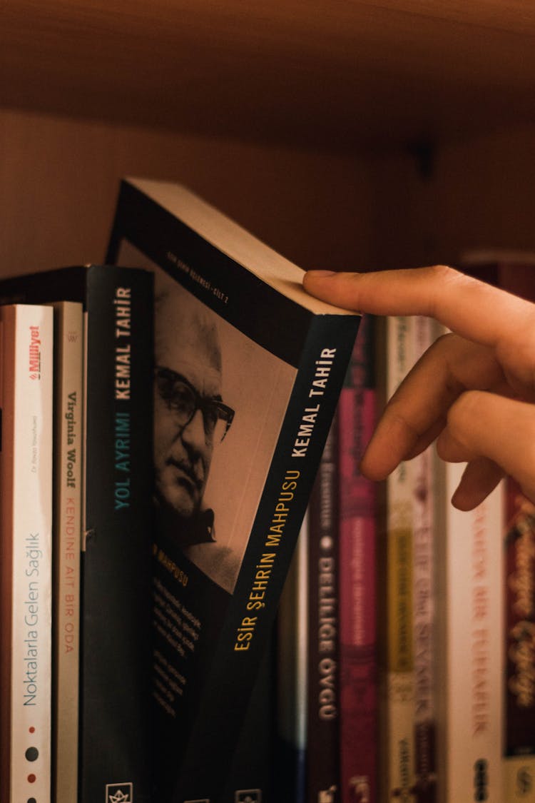 Faceless Person Picking Book From Home Library