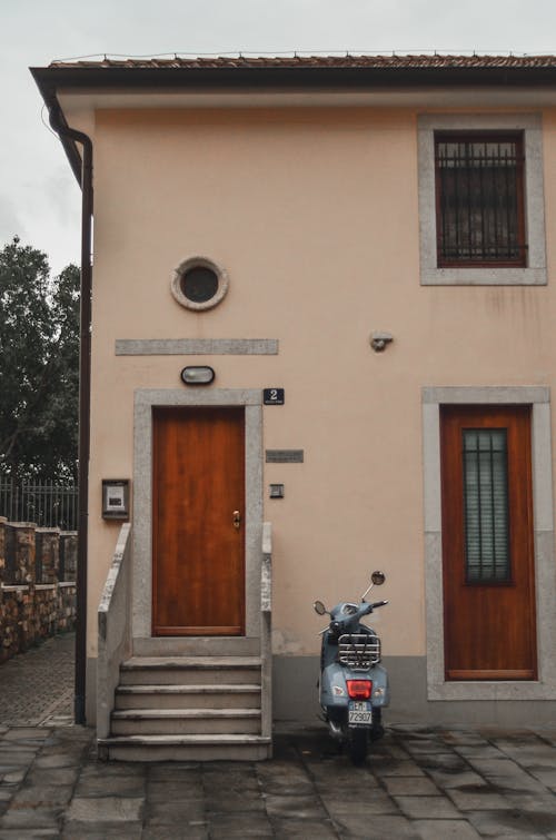 A Light Blue Vespa Parked near the Entrance of the House