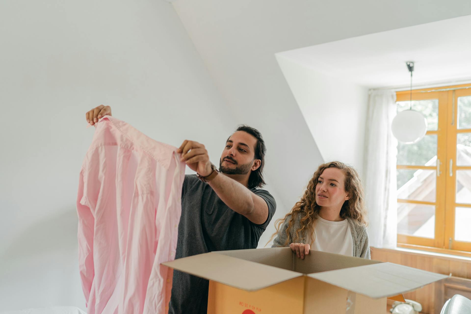 A happy couple unpacking boxes in their new home, enjoying the moving process.