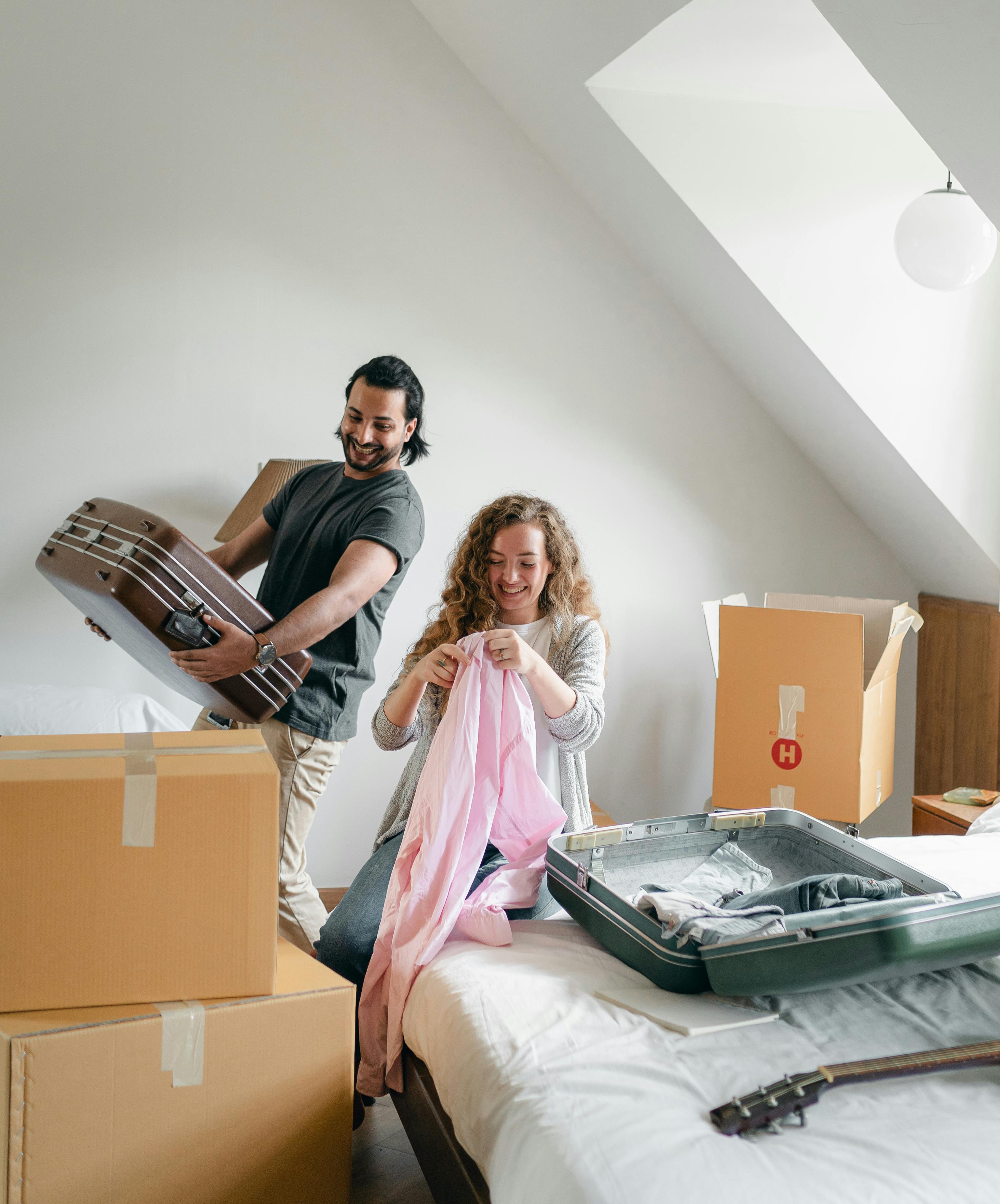 cheerful couple packing boxes and suitcases