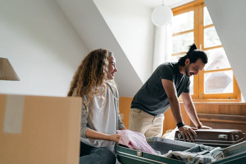 Cheerful couple packing suitcases and carton boxes