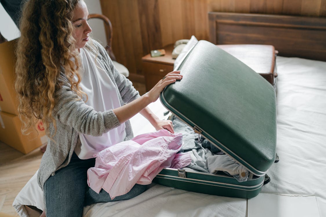 Focus woman packing suitcase on bed