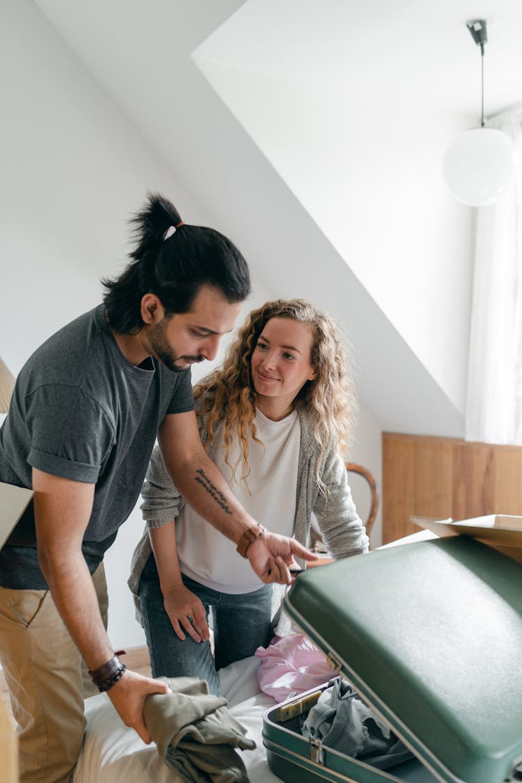 Cheerful Couple Packing Suitcase In Sunny Bedroom